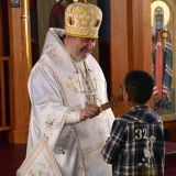 His Eminence Irénée smiles as he offers the cross to a young boy